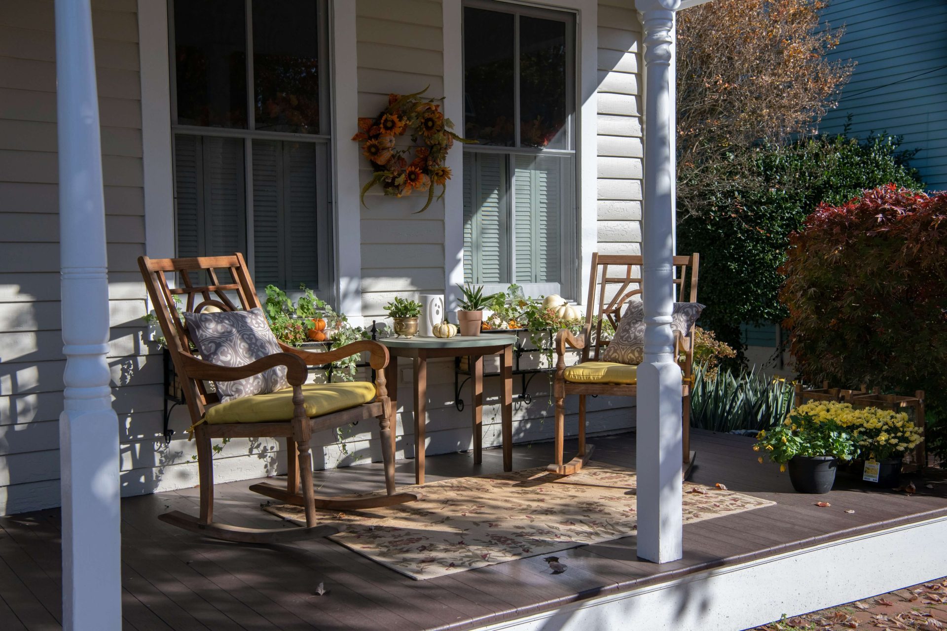 two wooden chairs and a table on a front porch