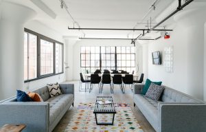 a living room with gray couches and black window frames