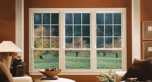 three double hung windows in an autumn colored living room with trees outside