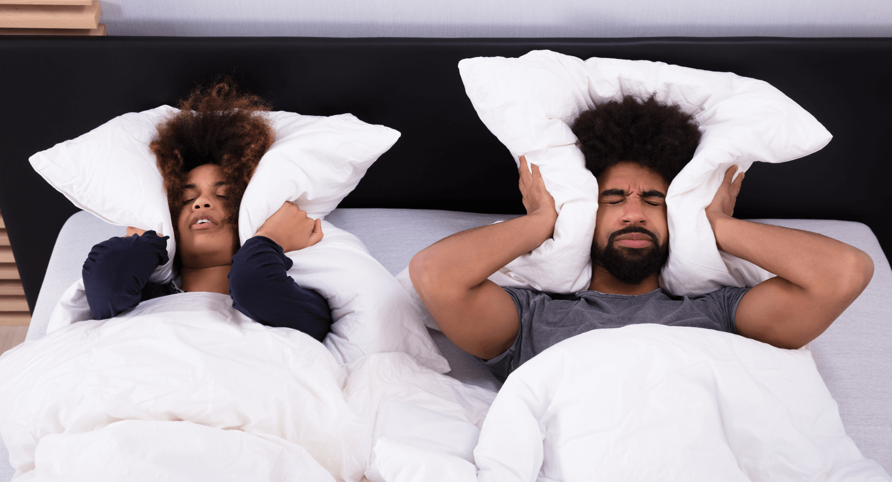 Image of a couple holding pillows over their ears