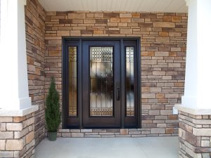 a front porch with one small plant and frosted glass windows on the entry door