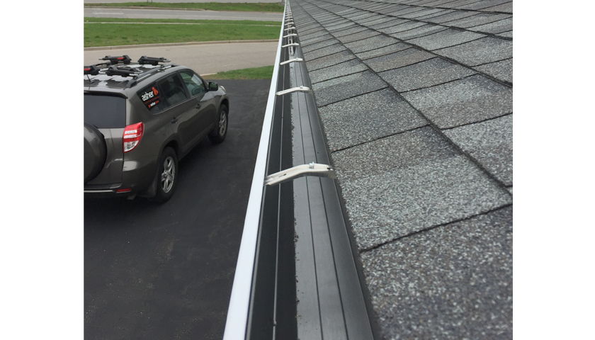 a house roof and gutters with the gutter installer's car in the driveway