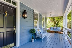a blue front porch with a bench and a hanging swing