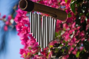 unique wind chimes in front of a pink plant