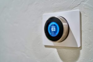 a smart thermostat on a white wall with the temperature set at 63