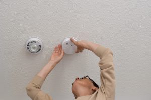 a woman checking a smoke detector on the ceiling