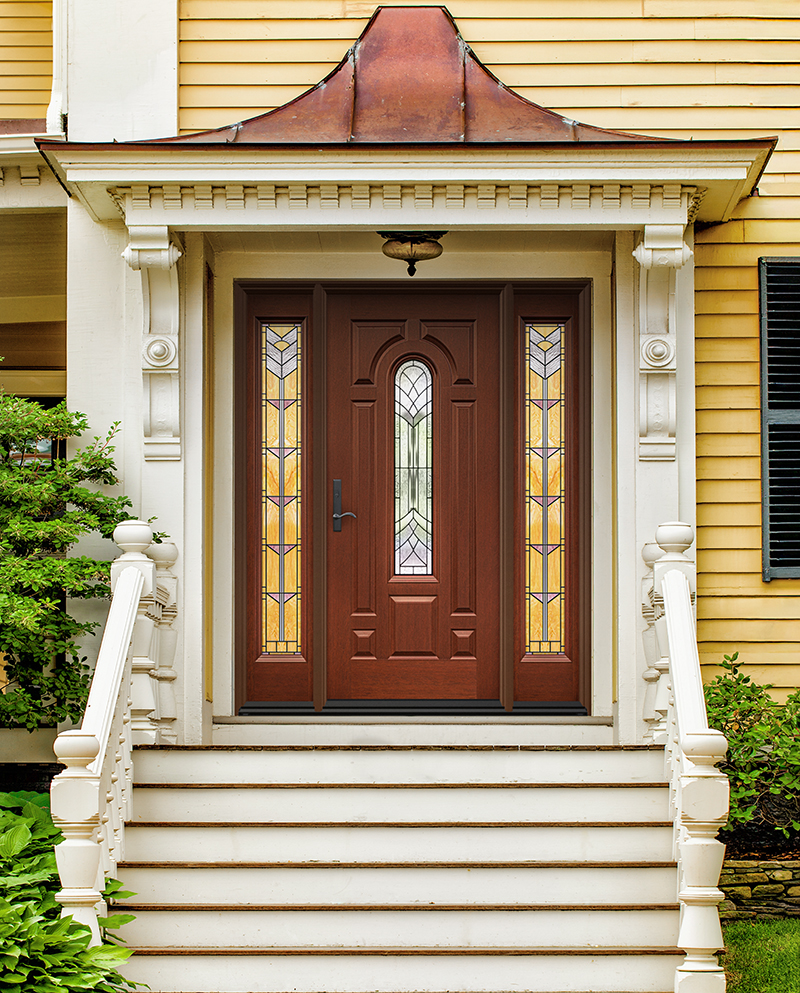 Front door of a vintage yellow house with white trim and a copper gable over the entry